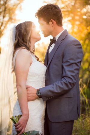 Bride and groom share romantic moment in golden sunlight.