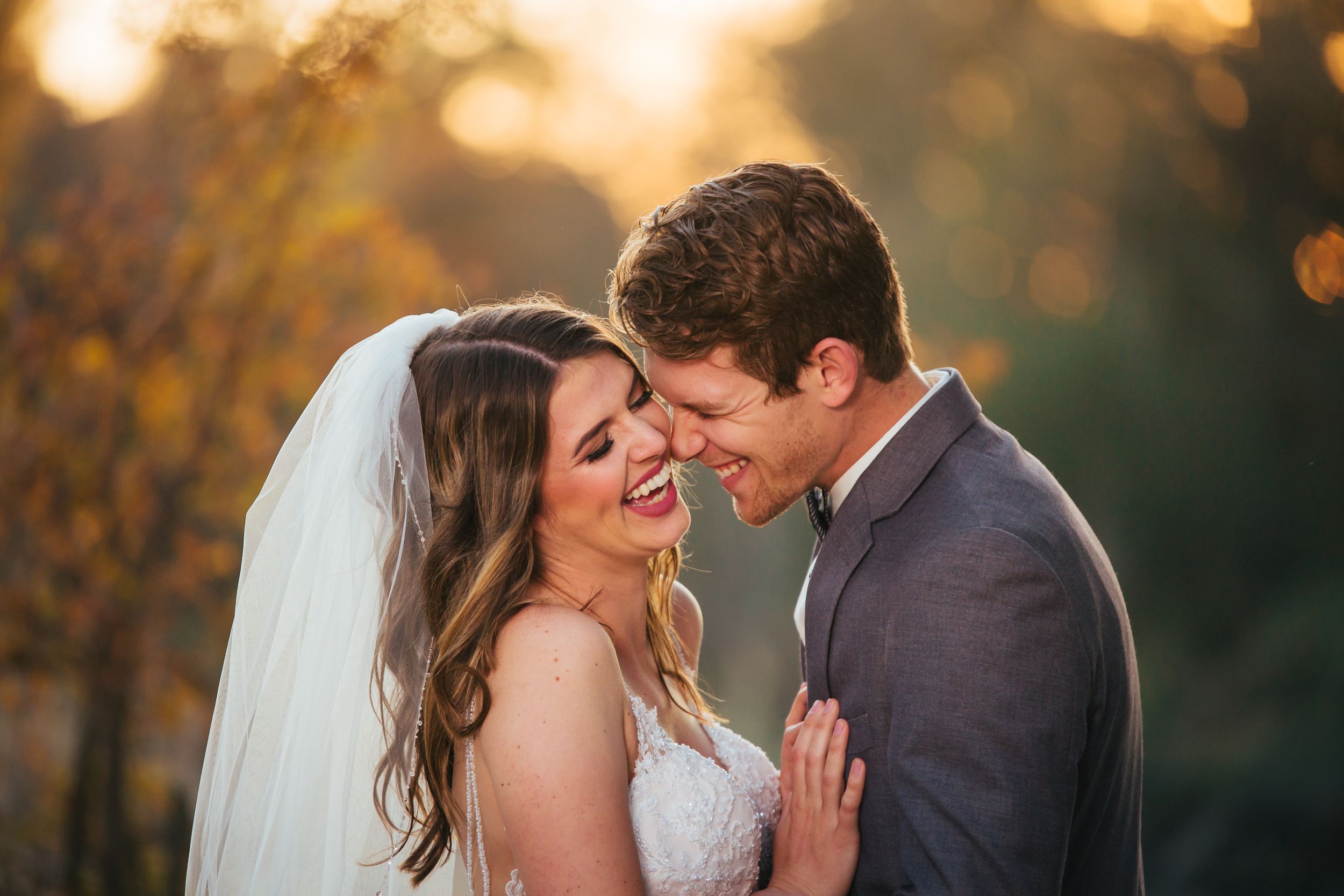 A romantic sunset wedding portrait of a couple sharing an intimate moment in golden light.