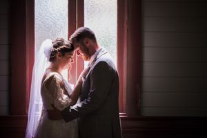 Intimate silhouette of wedding couple in window light creates romantic atmosphere.