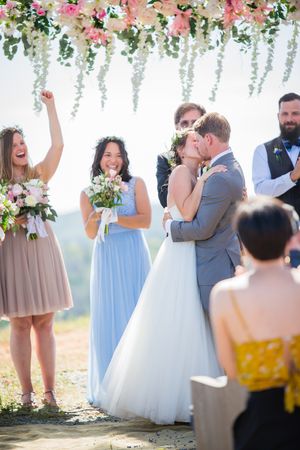Wedding ceremony under floral arch with pink and white blooms cascading from above.