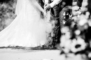 Artistic black and white detail shot of a wedding dress hem with smoke effects.