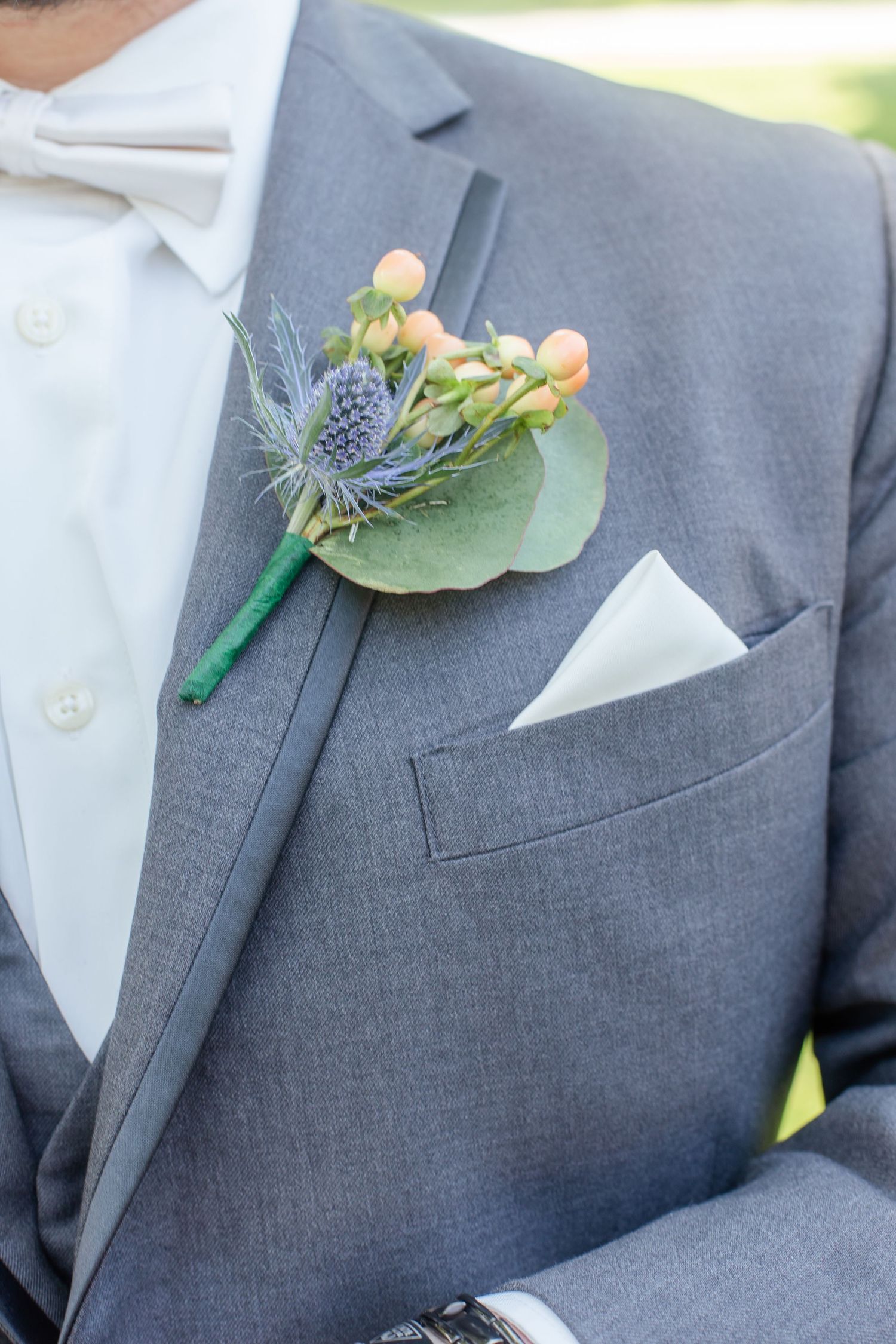 Grey suit lapels adorned with delicate floral boutonnieres in coral and blue tones.