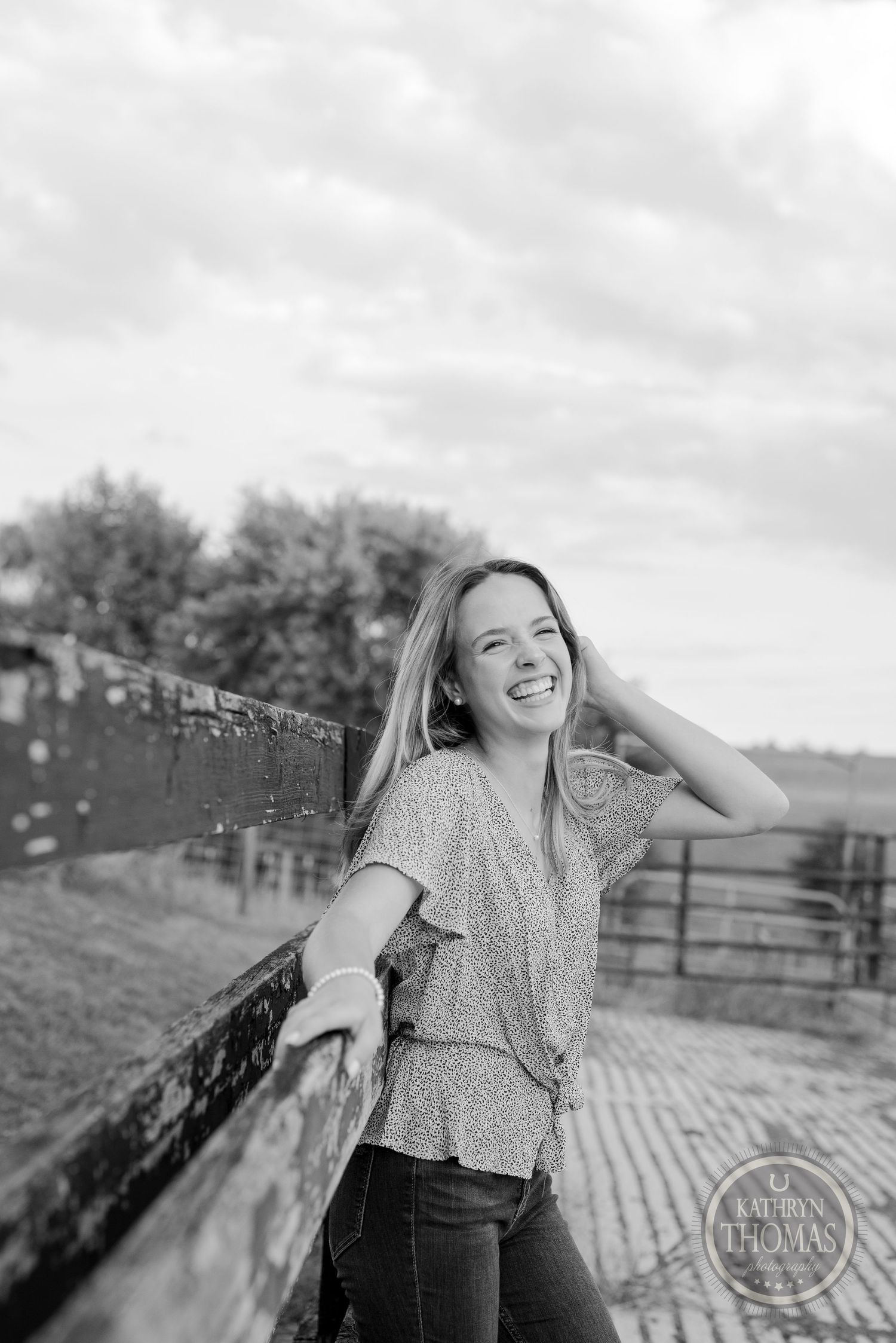 Black and white portrait leaning on fence with joyful expression.