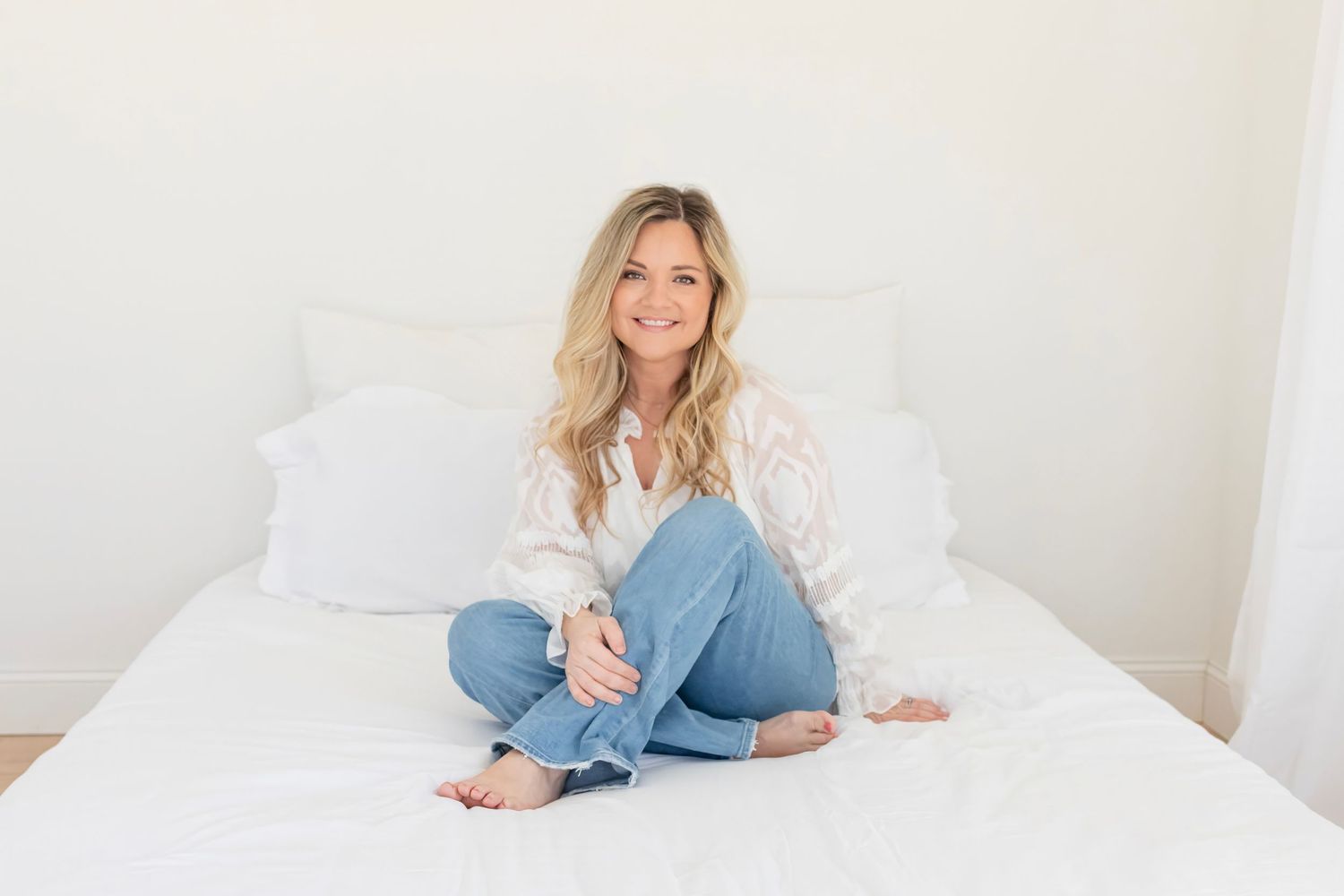 Lifestyle photography session on white bedding featuring casual denim and relaxed poses.