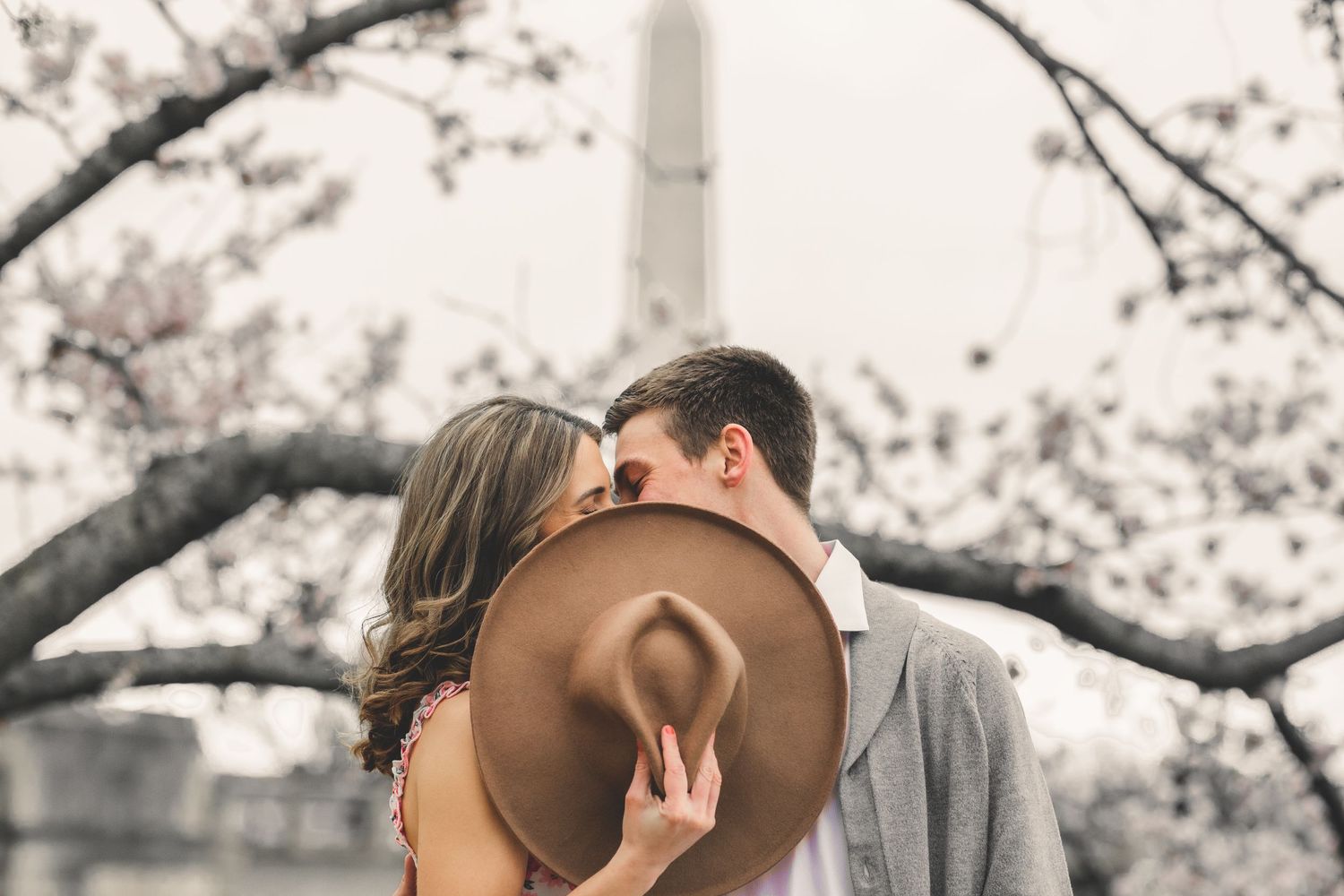 Couple posing by cherry blossoms at Tidal Basin with Washington Monument in background