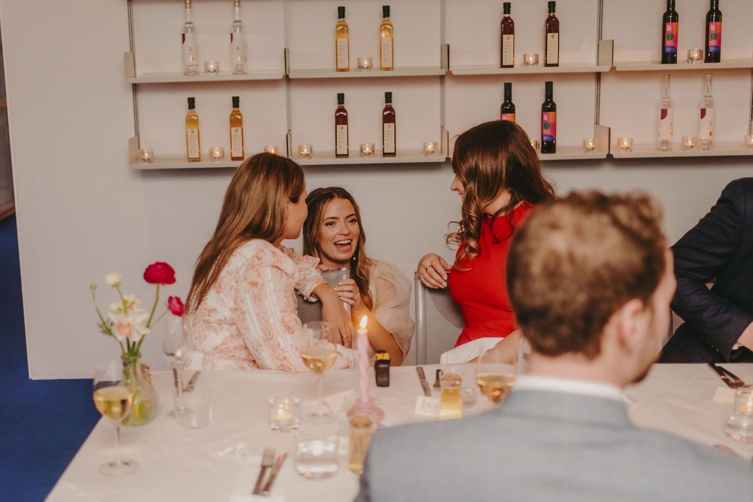 Wedding guests enjoying drinks and conversation at a bar during a reception celebration.