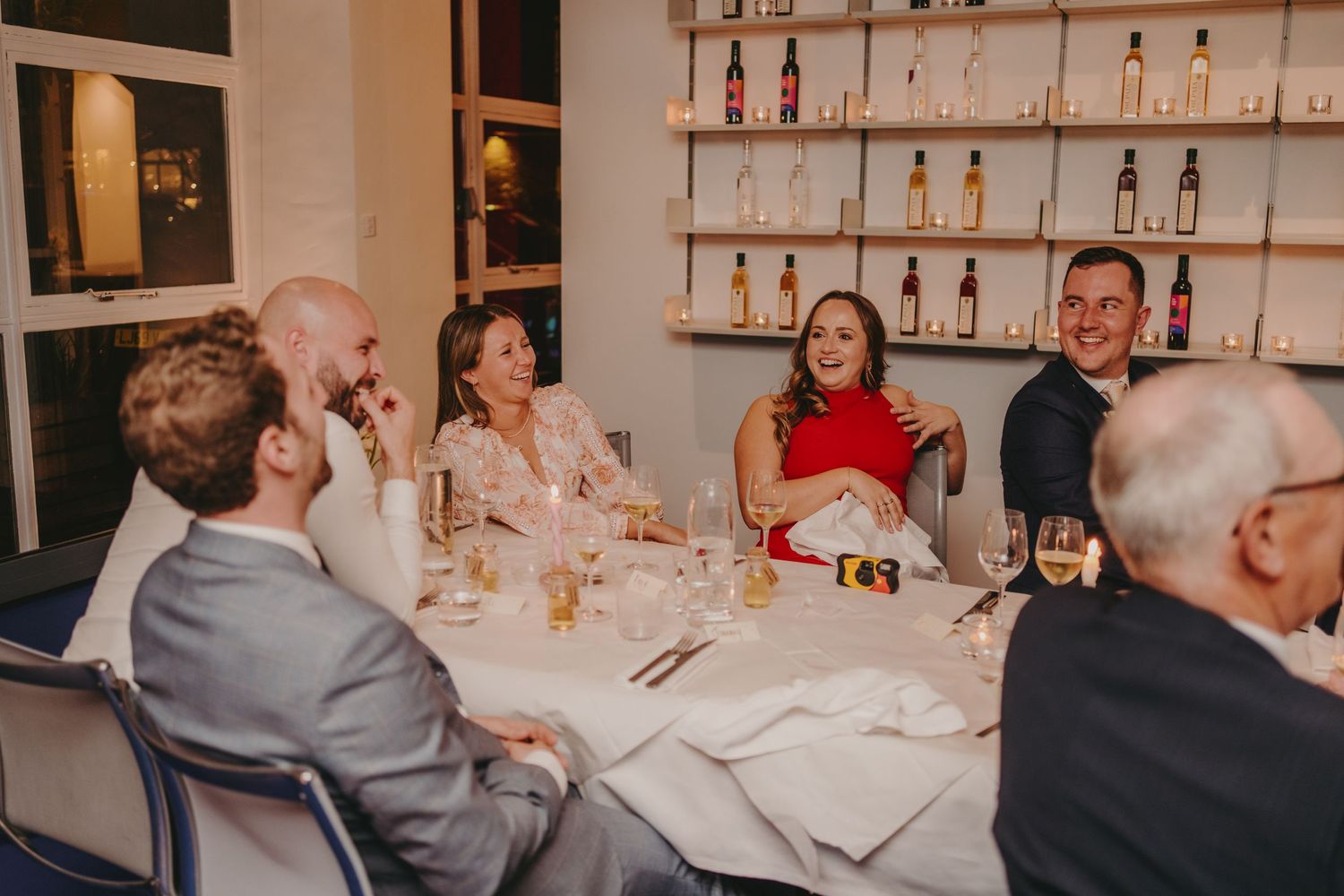 Formal dinner gathering at a restaurant with well-dressed guests seated around a white-clothed table.