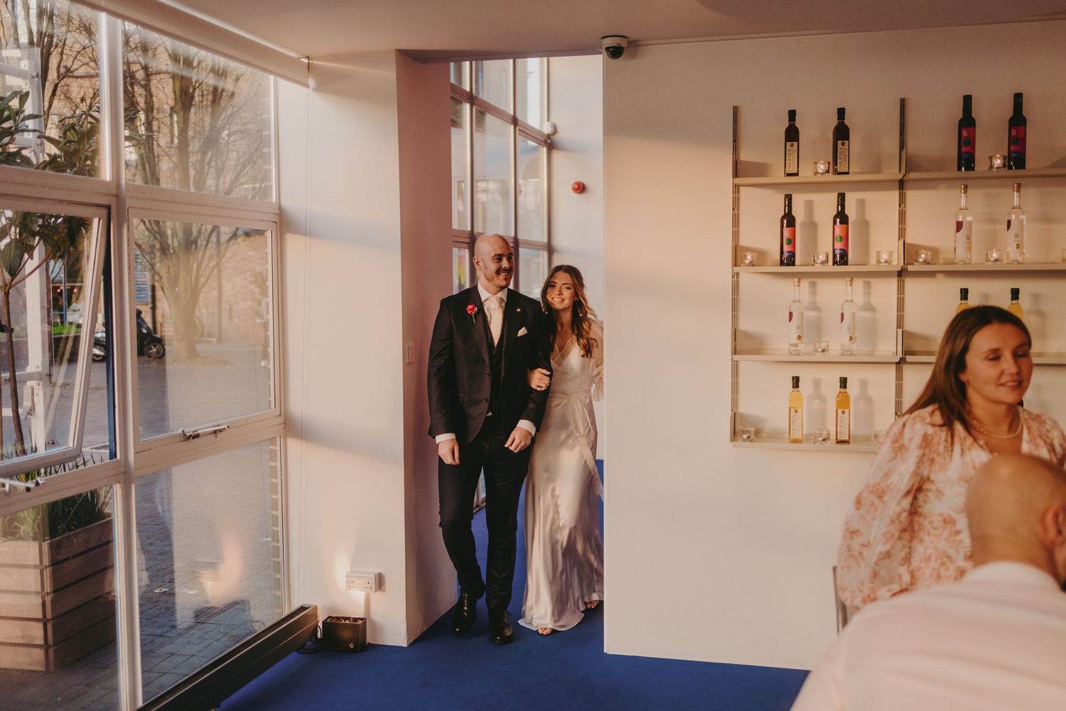 Modern interior event space with white walls and display shelves of bottles.