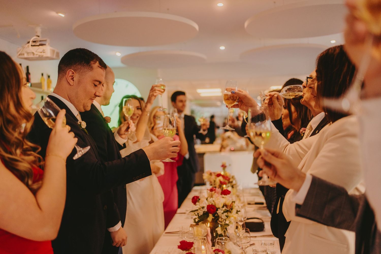 Celebratory toast during an elegant dinner party with warm ambient lighting.