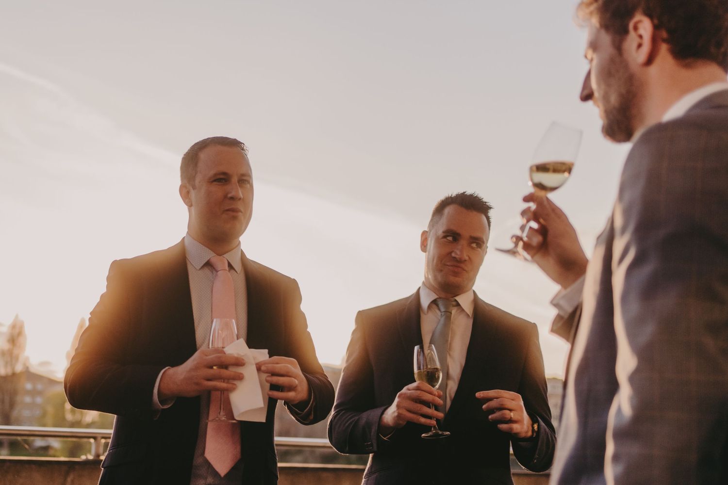 Group of guests enjoying champagne during sunset outdoor reception.