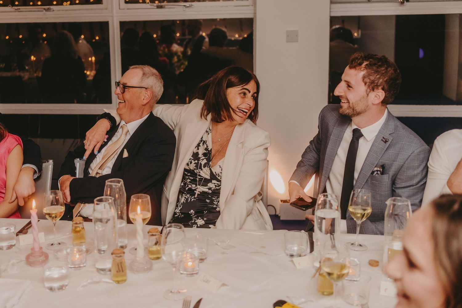 Wedding guests enjoying a reception dinner at a formal table setting with wine glasses.