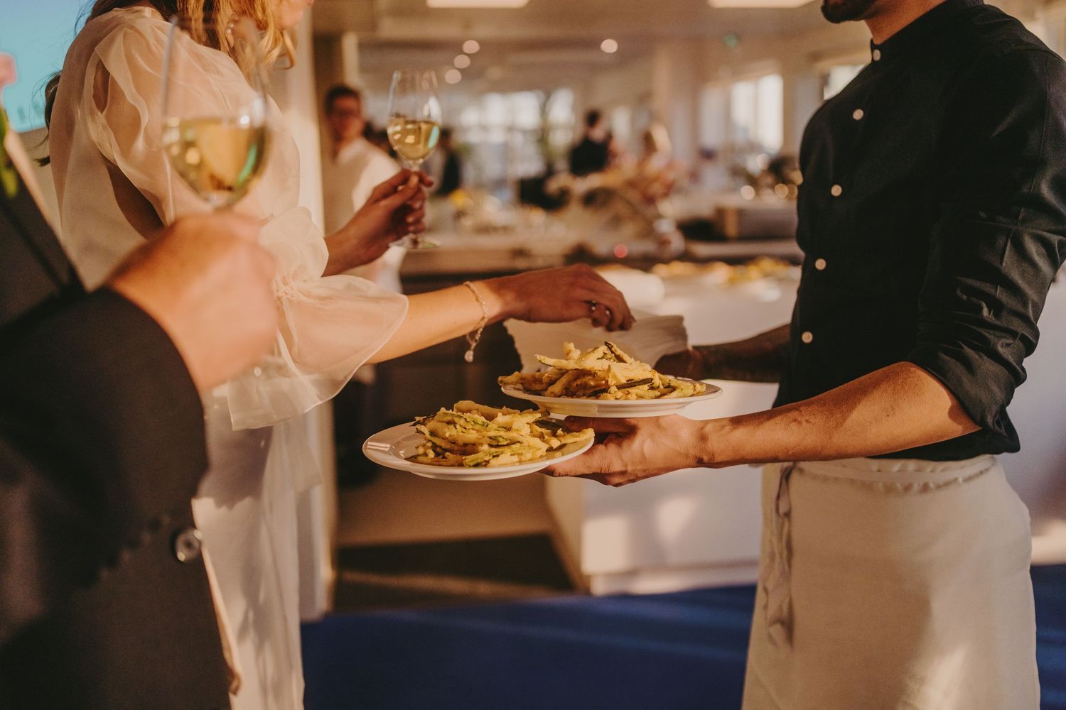 Food service staff plating and serving dishes at an upscale event.