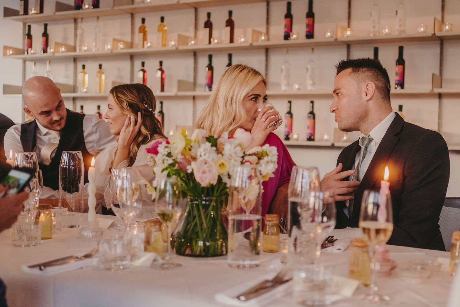 Intimate dinner conversation at wedding reception with candlelight and floral centerpieces.