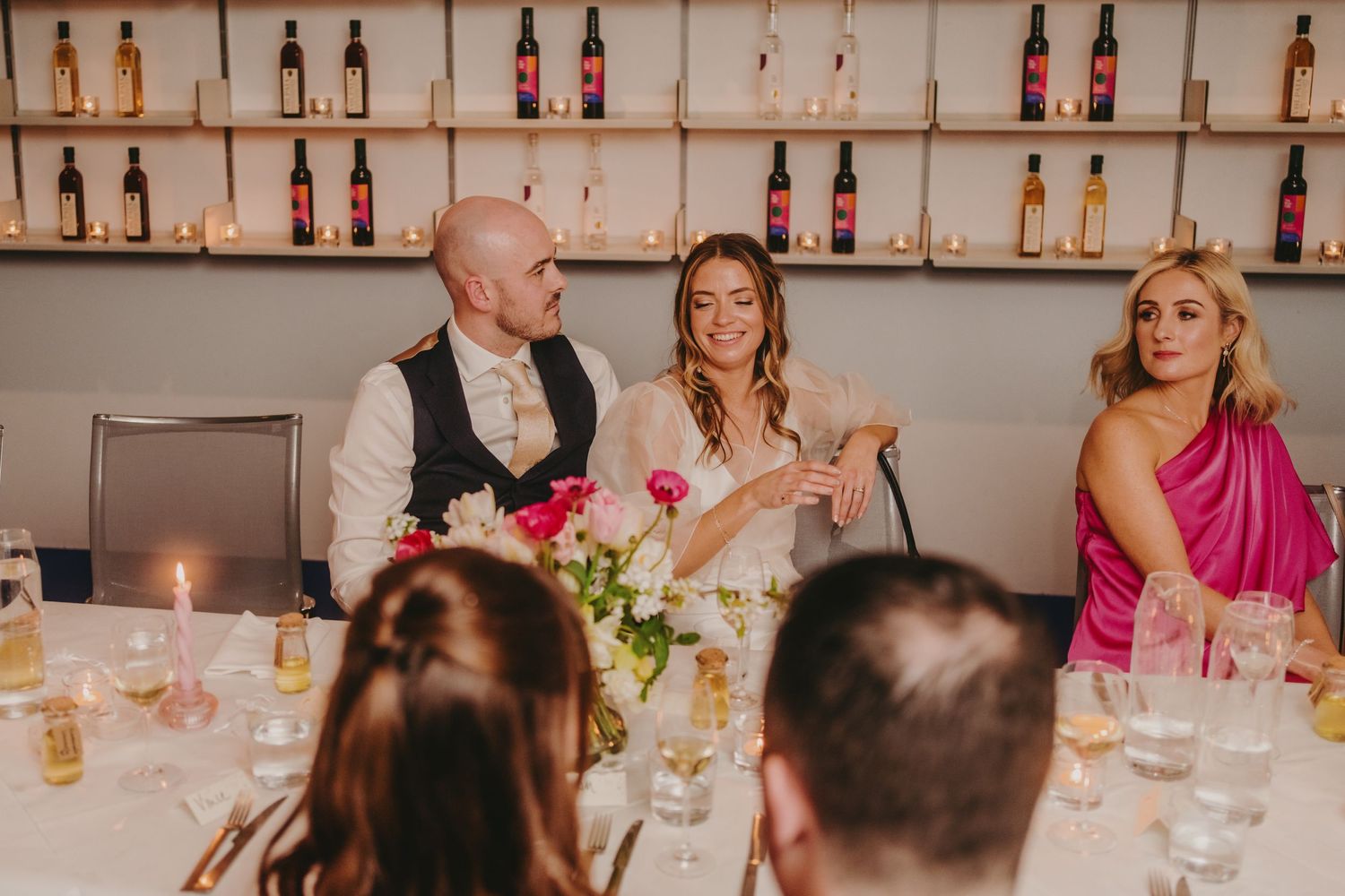 Wedding reception dinner scene with guests seated at tables decorated with floral centerpieces.