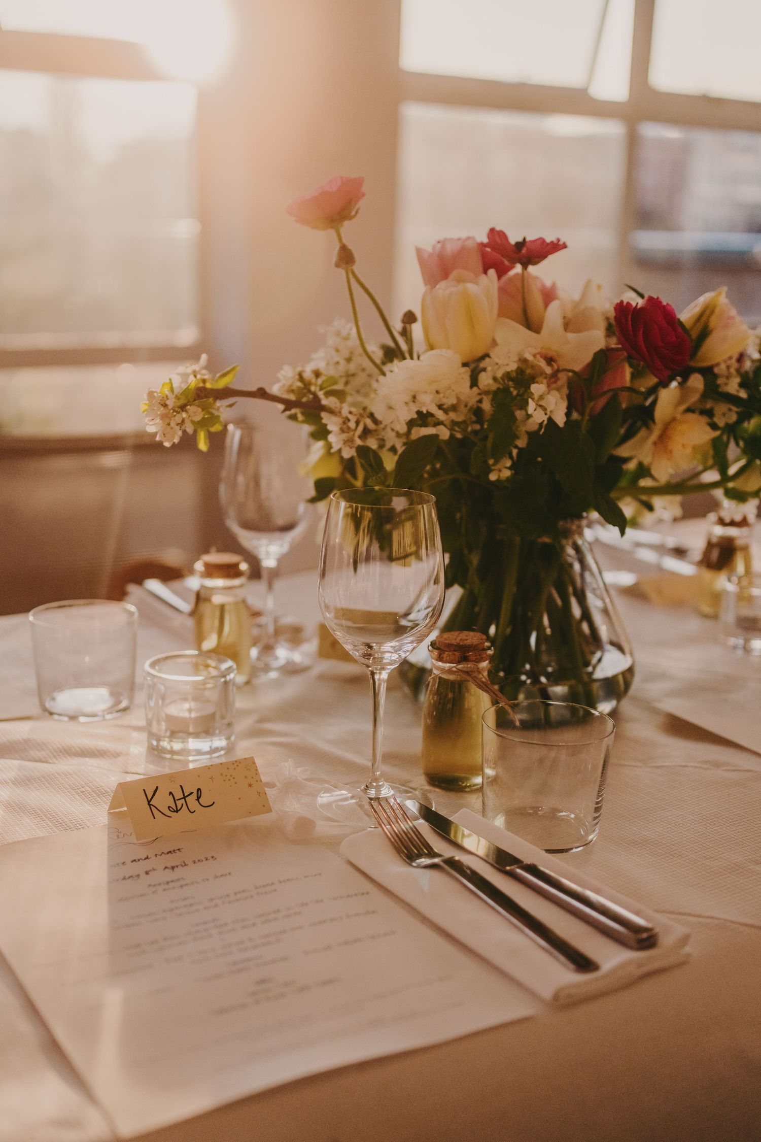 A romantic table setting with fresh floral arrangements, menus, and wine glasses.
