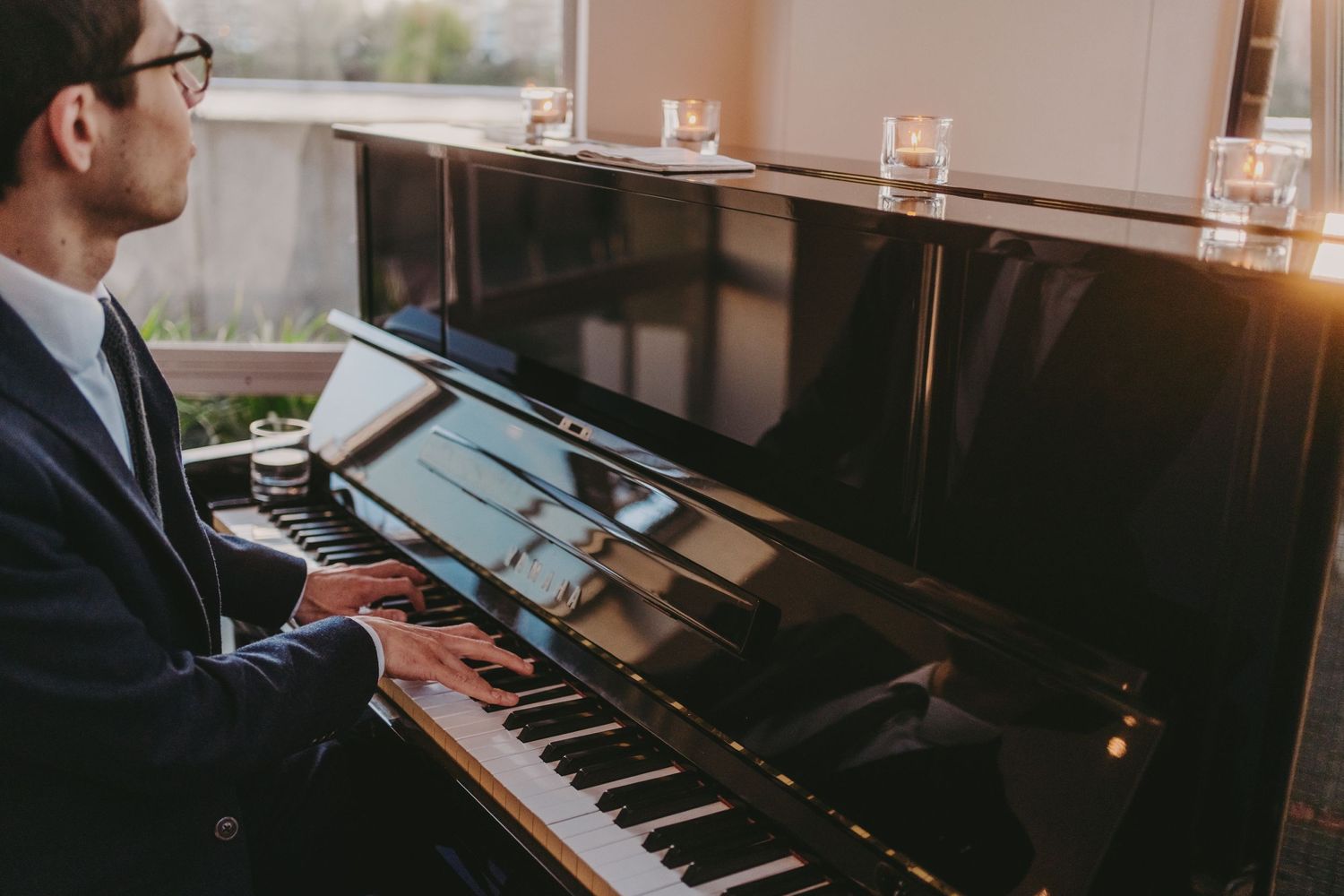 Pianist playing grand piano during elegant evening event.