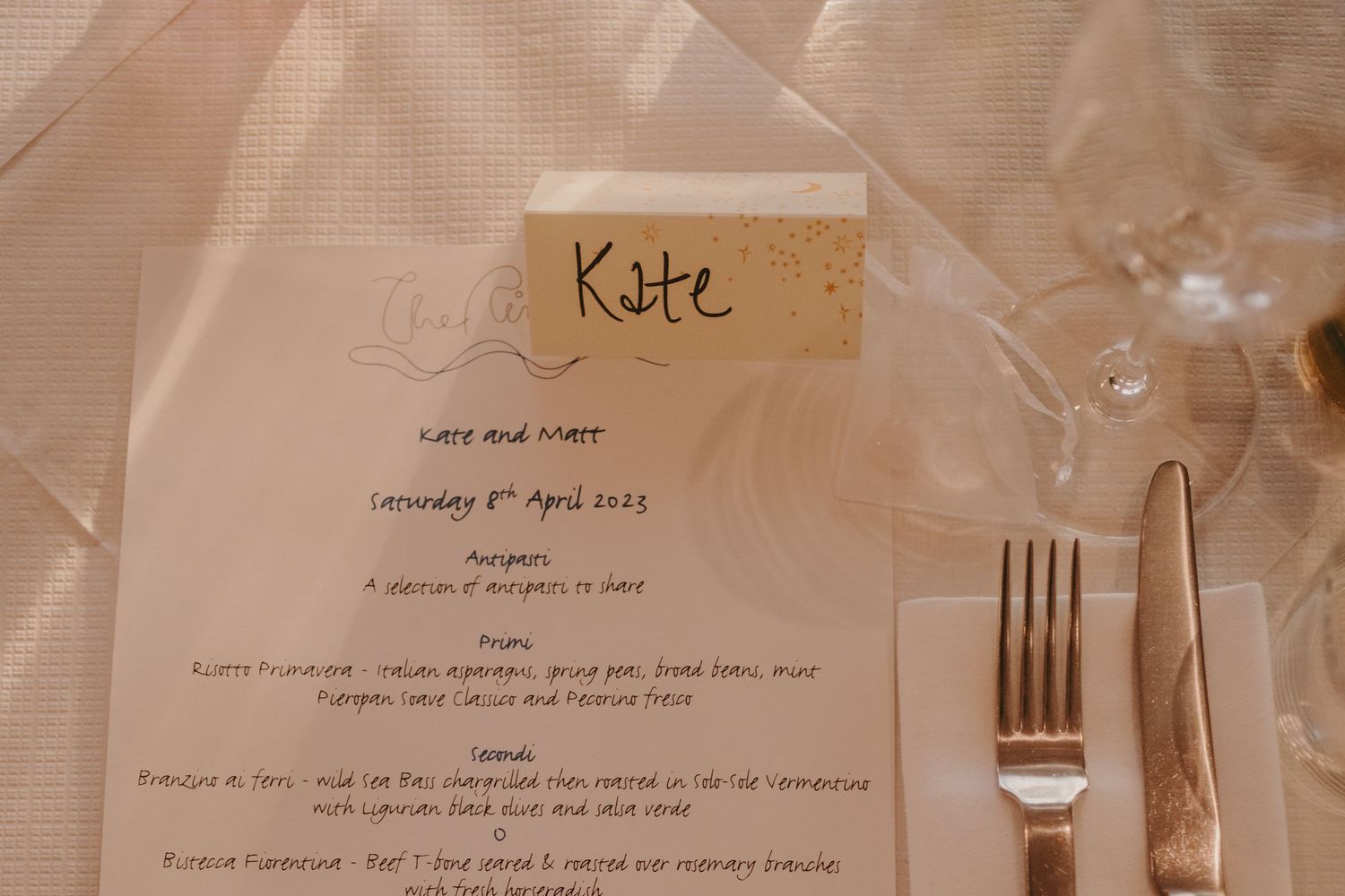 Wedding menu card labeled 'Kate' with silverware on white tablecloth.