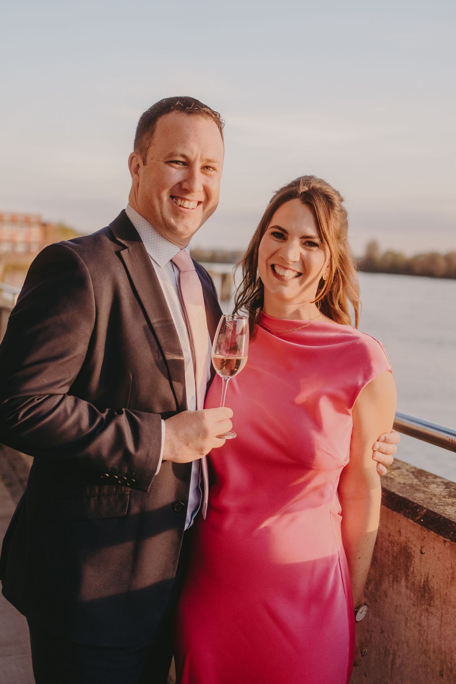 A happy couple poses with champagne glasses during their waterfront celebration.