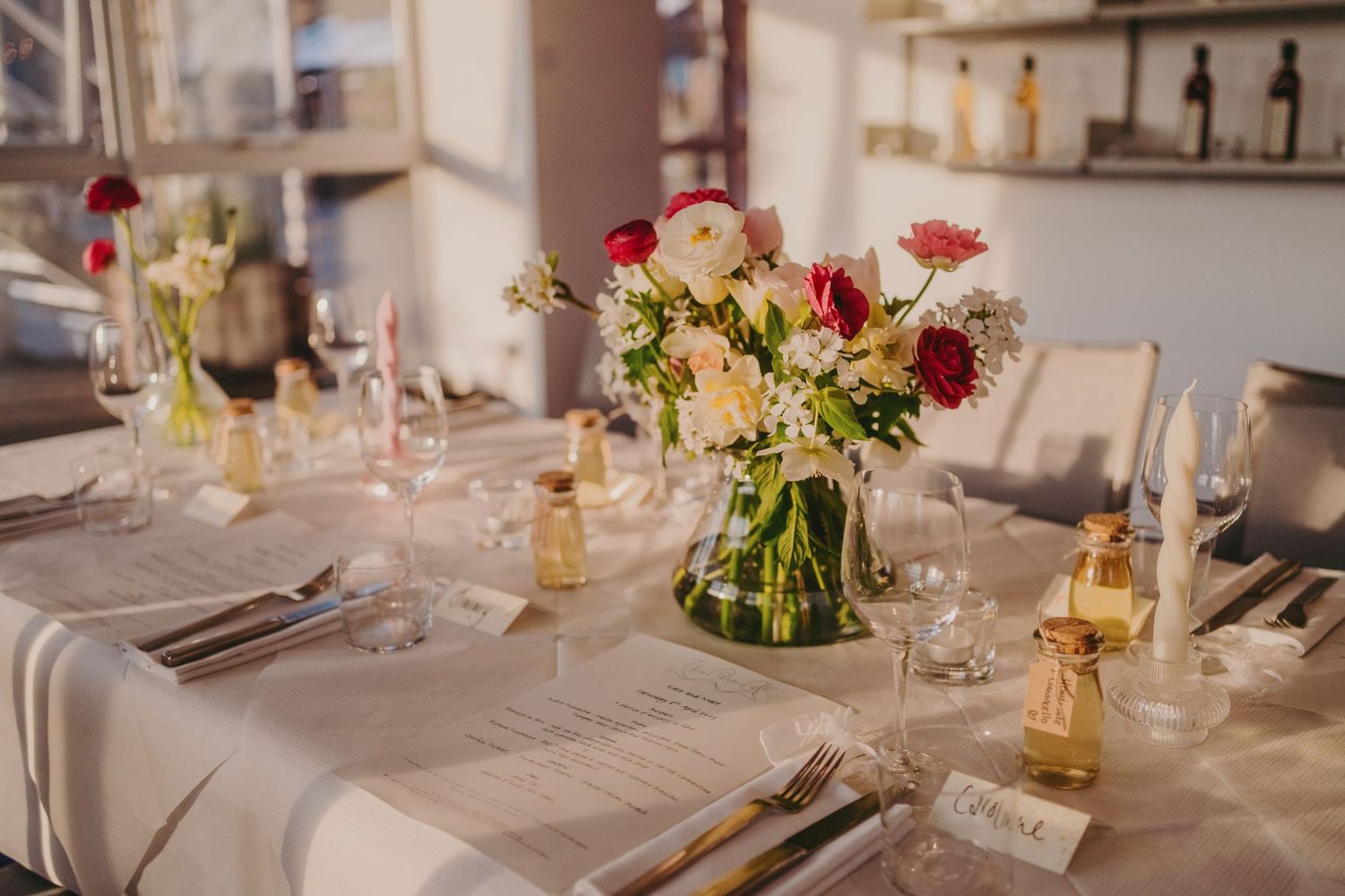An elegantly set wedding reception table with floral centerpieces and place settings.