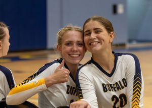 Photograph of Peyton and Anna smiling on the bench, Buffalo High School volleyball.