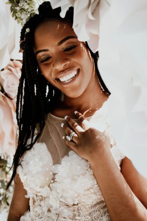 Joyful bride in a lace dress with long braids and a radiant smile.