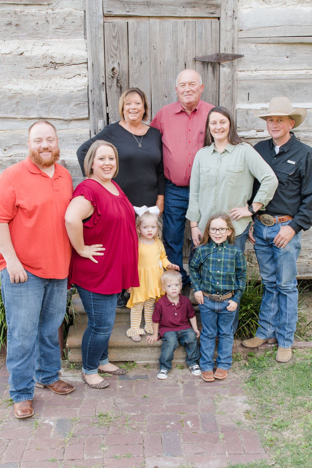 Family portrait of multiple generations in front of rustic wooden building.