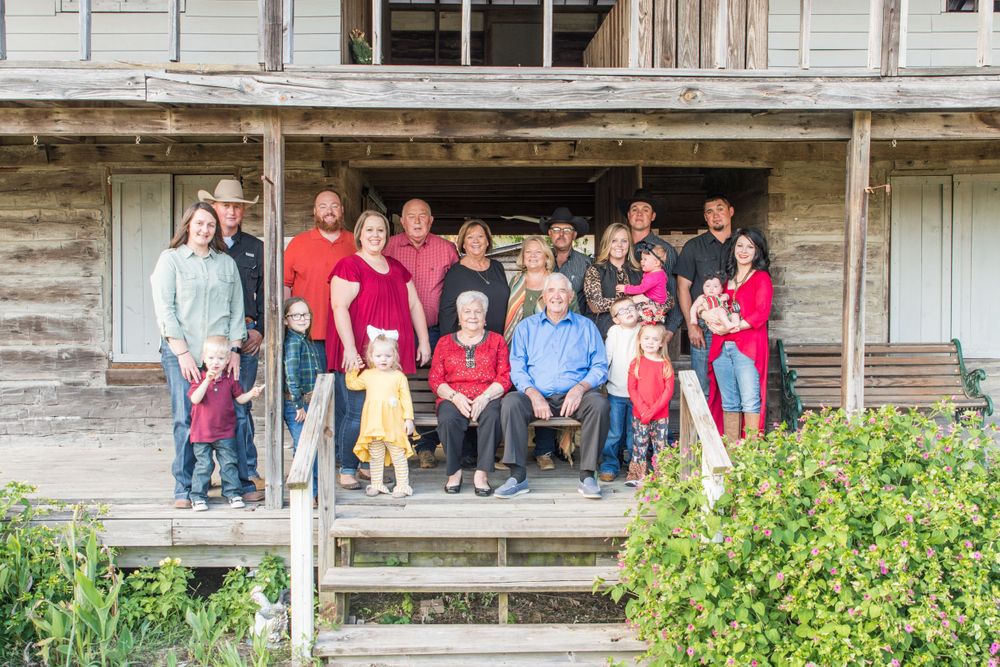Large multi-generational group gathered on rustic wooden porch steps for family photo.