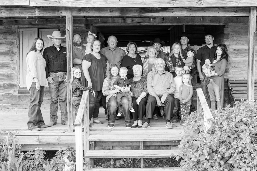 Black and white portrait of large family group seated on old wooden porch steps.