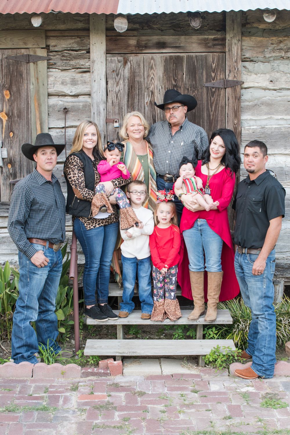 Western-styled family portrait with children in front of rustic wooden building.