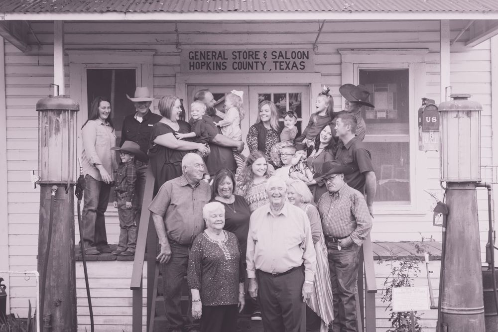 Vintage black and white photo of group gathered at old general store entrance.