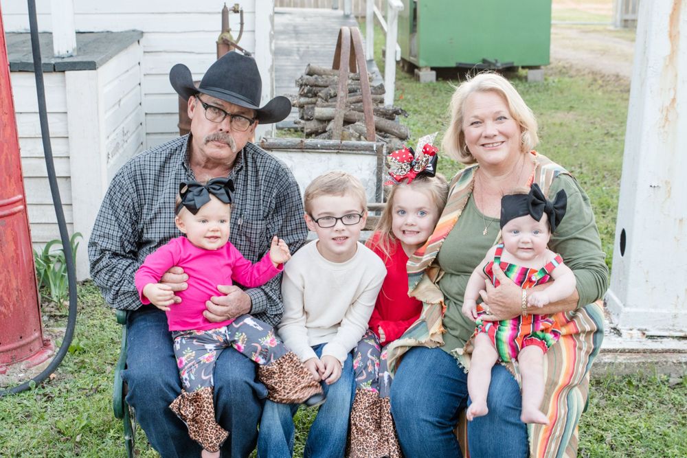 A multigenerational outdoor family portrait in front of a white building with three young children.