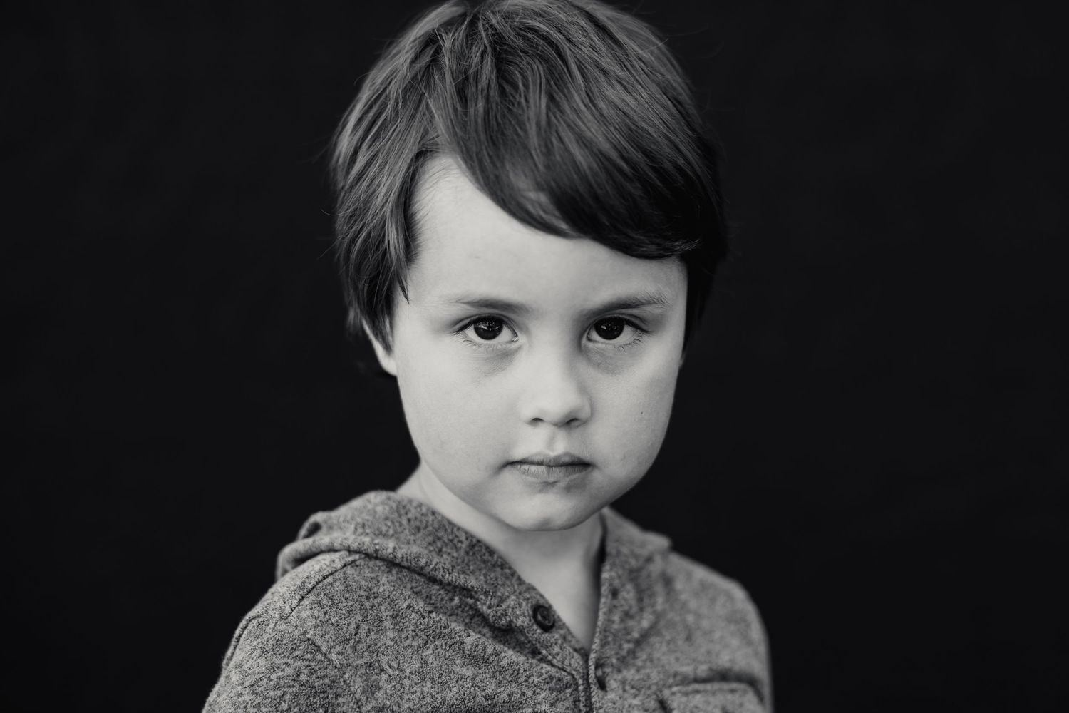 A serious black and white portrait of a young person wearing a hooded sweatshirt.