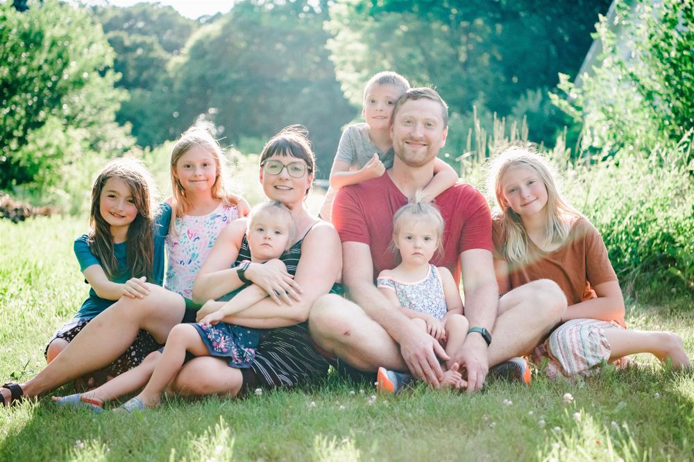Happy family sitting together on grass during sunny summer day outdoors.