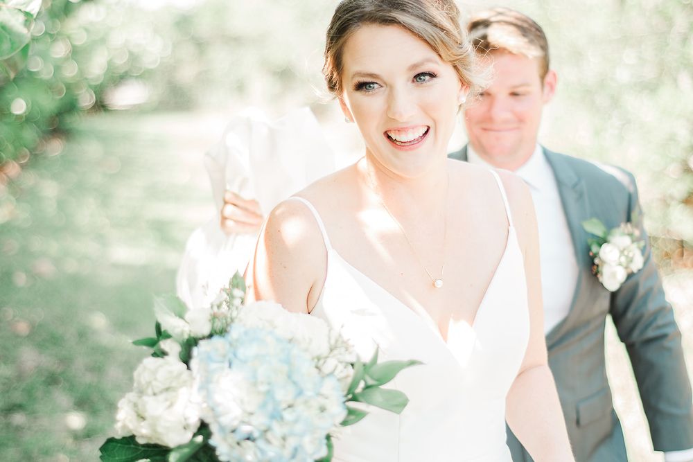 A wedding couple posing in a garden setting with a soft-focus floral background.