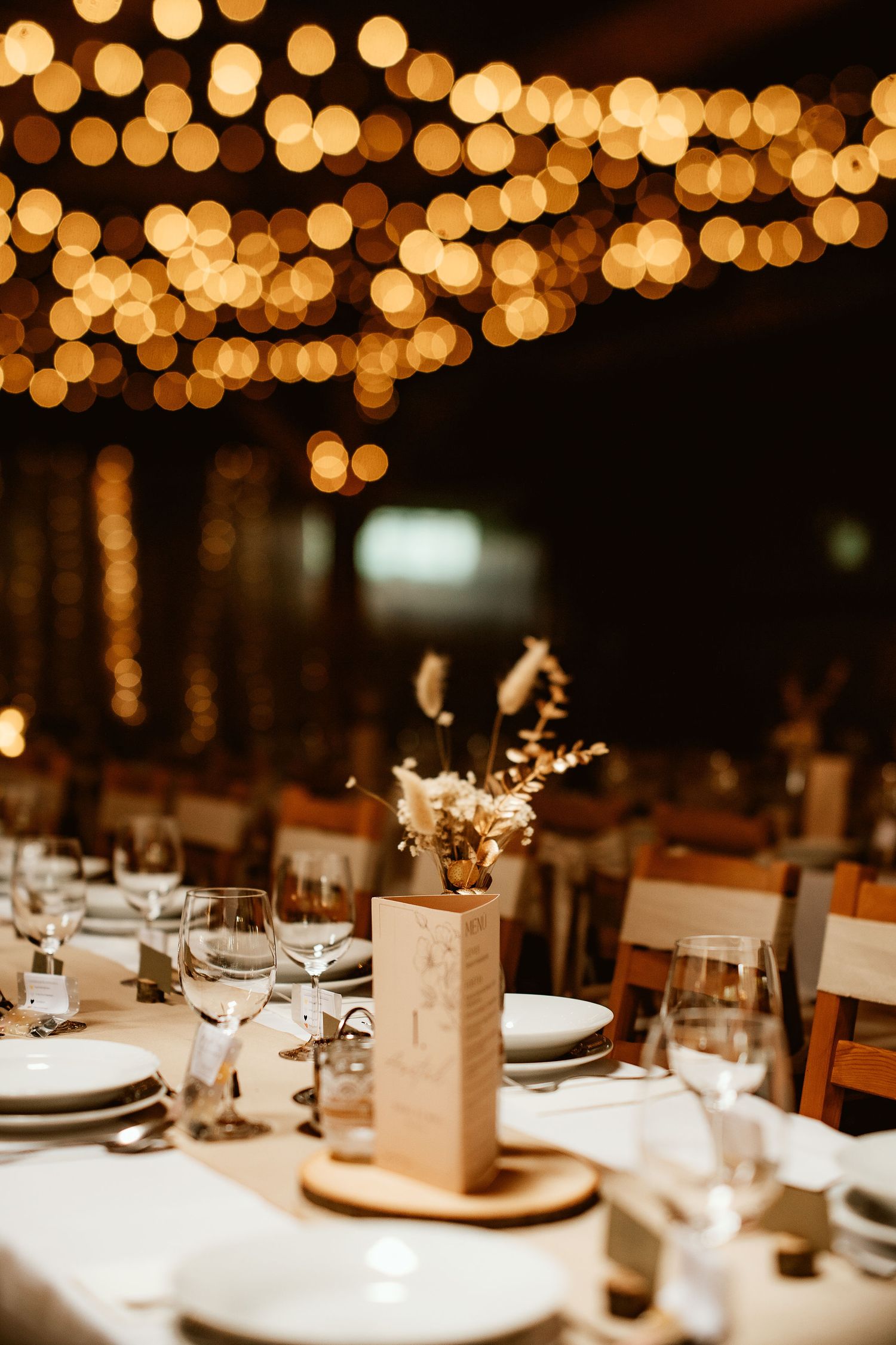 Intimate wedding table setting with warm bokeh lights and rustic centerpieces.