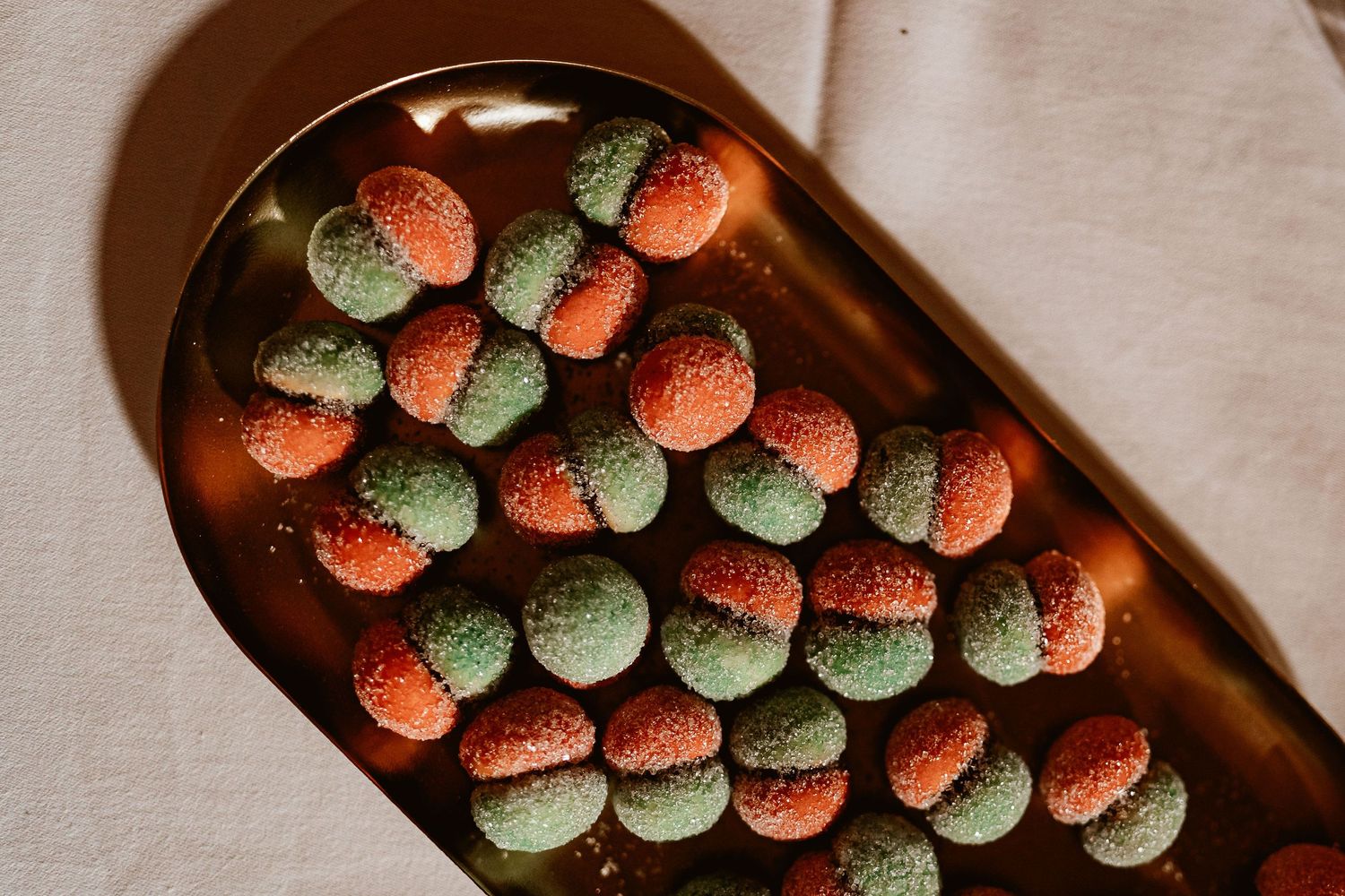 Colorful macarons arranged in alternating red and green pattern on dark serving platter.