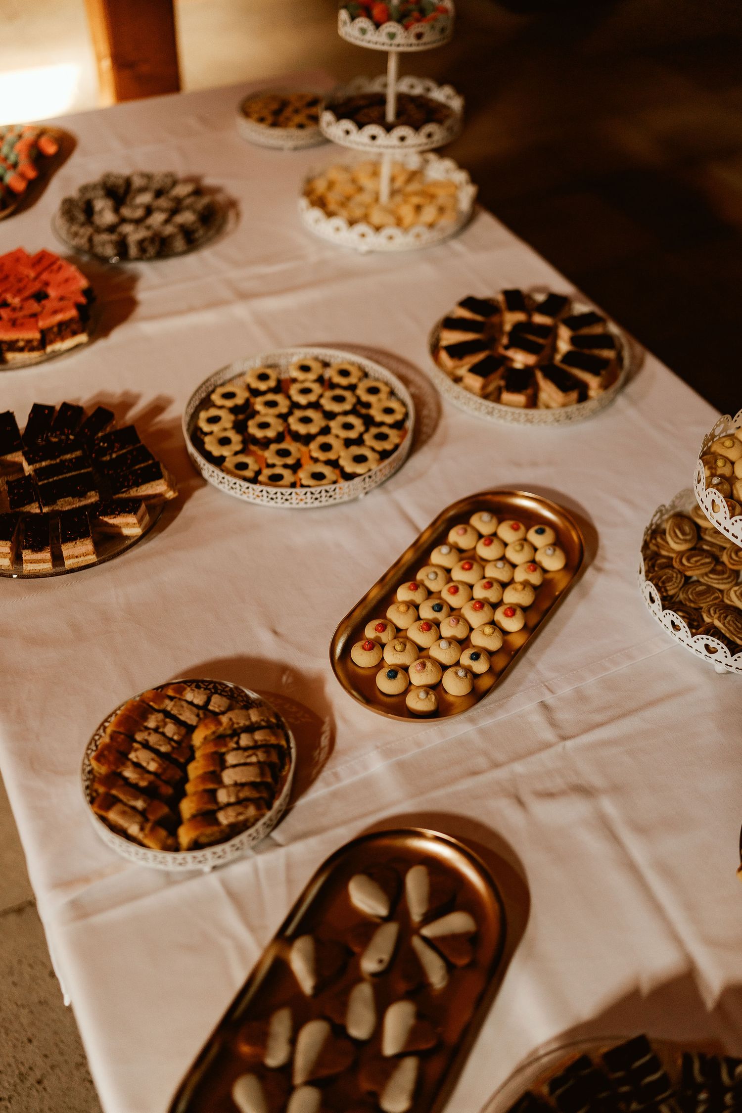 Wedding dessert table with assorted cookies and treats displayed on ornate serving platters.