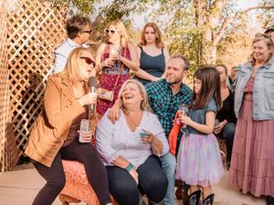 People celebrating and raising drinks during a festive outdoor party with decorative lattice backdrop.