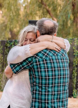 Intimate moment between couple surrounded by willow trees and party decorations.