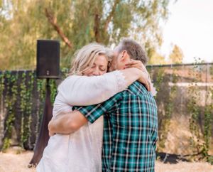 Romantic outdoor scene with couple embracing under string lights and natural foliage.