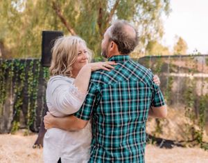 Intimate moment captured in outdoor venue with decorative lighting and natural backdrop.
