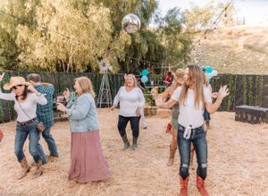 Guests dancing and mingling at a casual outdoor party with string lights in a desert setting.