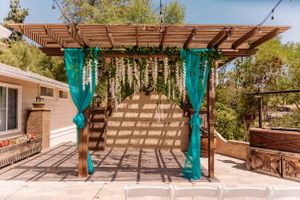 Wooden pergola decorated with turquoise fabric drapes in a desert setting.