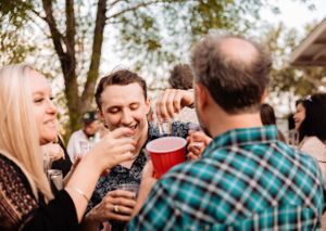 Guests mingling and socializing at an outdoor party with string lights overhead.