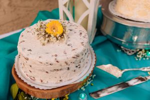 Close-up of decorated white cakes with floral accents on a turquoise tablecloth.