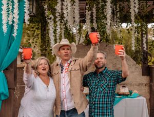 People cheering with red plastic cups at an outdoor party with teal and white decor.