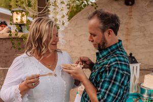 Celebratory moment between guests at an outdoor party with teal curtains and hanging flowers.