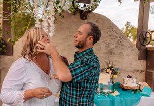 Intimate celebration moment between guests at a decorated outdoor venue with teal accents.