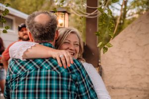 Joyful embraces shared between guests at an outdoor party with teal and floral decor.