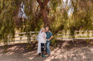 Couple sharing tender moments under a willow tree in natural lighting.